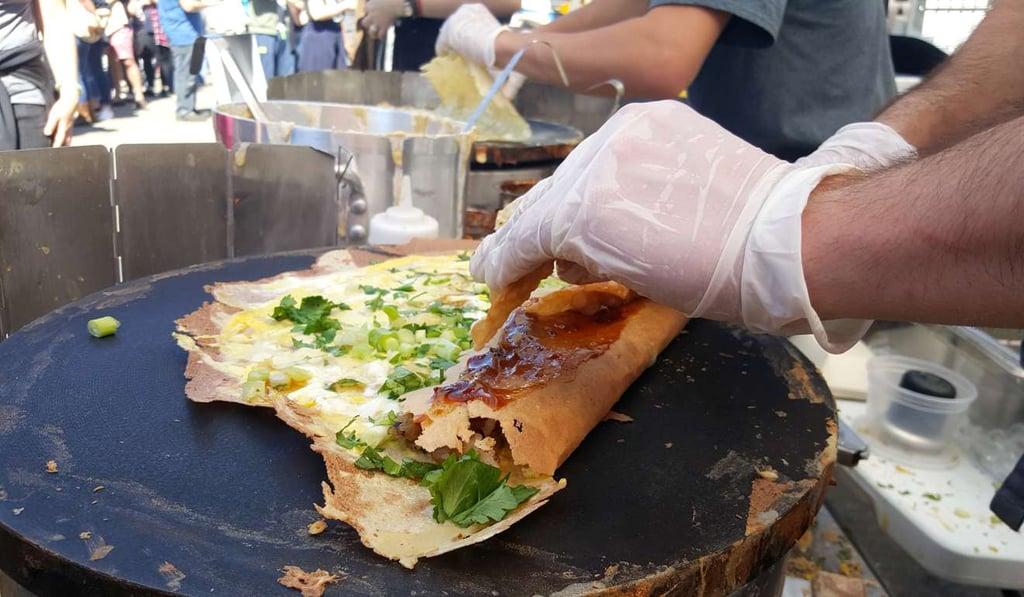 Freshly prepared Chinese jianbing savoury pancake at a street breakfast stall